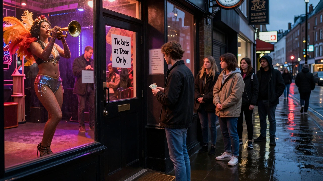A person waiting outside The Box venue at night, holding cash, as a vibrant cabaret show unfolds inside through the glass door.